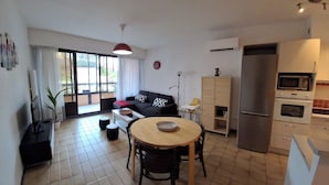 Una cocina moderna con refrigerador, microondas y horno. Hay un comedor con mesa y sillas.