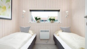 A room with two beds, a window with a view, a wall-mounted heater, and a framed picture. - 4 Star Holiday Home in Grossenbrode (Grossenbrode)