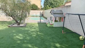 A backyard with artificial grass, a small tree, a playhouse, and a soccer goal. - Charming studio-cabin in quiet location near Nîmes and beaches (Bouillargues)