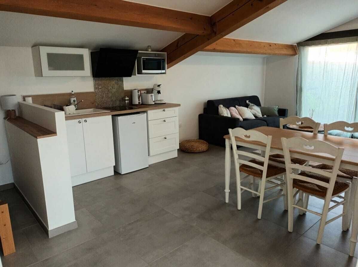 Une cuisine compacte avec des meubles blancs, un four à micro-ondes et un coin repas doté de chaises en bois.