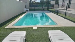 A rectangular pool with two white lounge chairs in the foreground. - Charming studio-cabin in quiet location near Nîmes and beaches (Bouillargues)