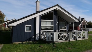 Ein modernes Haus mit einer großen Terrasse, einem Schornstein und einem großzügigen Innenraum.