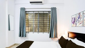 Ein Hotelzimmer mit Bett, Vorhängen, einem Fenster mit Blick und einem Kunstwerk an der Wand.