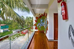 A corridor with a wooden floor, a glass railing, a mural, and a fire extinguisher. - Deluxe Celeb Da Luna (Chopdem)
