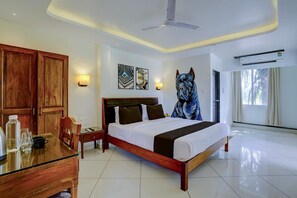 A hotel room with a bed, wooden wardrobe, bedside table, and artwork on the wall. - Deluxe Celeb Da Luna (Chopdem)