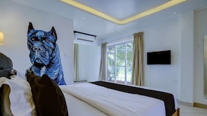 Ein Hotelzimmer mit einem großen Bett, einer Klimaanlage, einem Fernseher und einem Fenster mit Vorhängen.