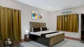 A bedroom with a bed, curtains, a bedside table with a lamp, and artwork on the wall.
