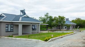 A modern building with a flat roof, a water tank on top, and a paved area with a small garden. - Tree Tops Game Resort Eswatini  (Big Bend)