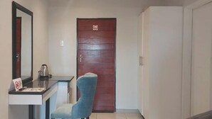 A room with a wooden door, a desk with a mirror, a chair, and a wardrobe. - Tree Tops Game Resort Eswatini  (Big Bend)
