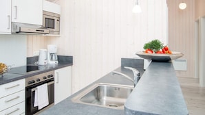 A modern kitchen with white cabinets, a built-in microwave, a stove, a sink, and pendant lighting. - 4 Star Holiday Home in Grossenbrode (Grossenbrode)