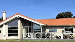 A single-story house with a red-tiled roof, large windows, and a fenced outdoor area. - 4 Star Holiday Home in Grossenbrode (Grossenbrode)