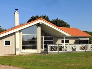 A single-story building with a red-tiled roof, large windows, and a fenced outdoor area. - 4 Star Holiday Home in Grossenbrode (Grossenbrode)