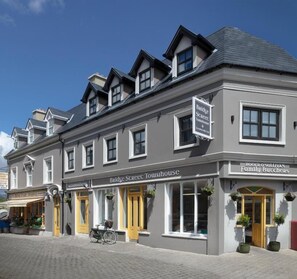 Un edificio de dos pisos con un letrero que dice 'Bridge Street Towhouse' y 'Roger O'Sullivan Family Butchers'.