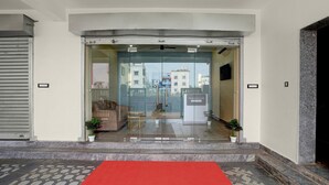 A hotel entrance with a red carpet, potted plants, and a view of buildings in the background. - Deluxehotel Pratee Heights (Bhubaneshwar)