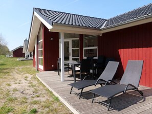 Um edifício vermelho com alpendre, área de estar ao ar livre e um terraço.