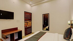 Une chambre d’hôtel moderne équipée d’un lit, d’une télévision, d’une armoire en bois et d’un panneau décoratif.