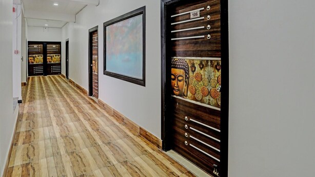 Un couloir doté d’un plancher en bois, d’un tableau représentant Bouddha et d’une porte avec une plaque numérotée.