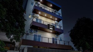 Un immeuble à plusieurs étages doté de balcons, de climatiseurs et d’une enseigne indiquant qu’il abrite les bureaux d’une entreprise.