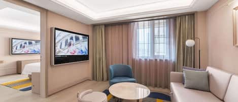 Una habitación de hotel con cama, televisor, sofá, sillón, mesita y alfombra.