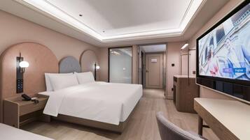 A hotel room with a bed, bedside table, TV, and a desk with a chair.