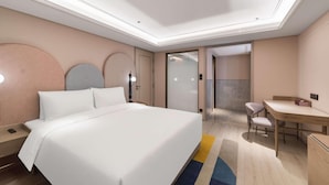 Quarto de hotel com cama, mesa de cabeceira, escrivaninha, cadeira e banheiro visível através de uma porta de vidro.