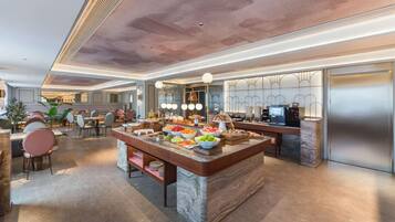 A spacious kitchen with a marble island, modern appliances, and a seating area with chairs and tables.