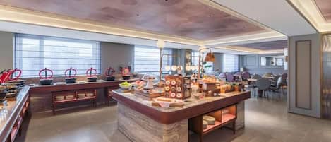 A buffet area with a marble island, multiple food stations, and seating arrangements.