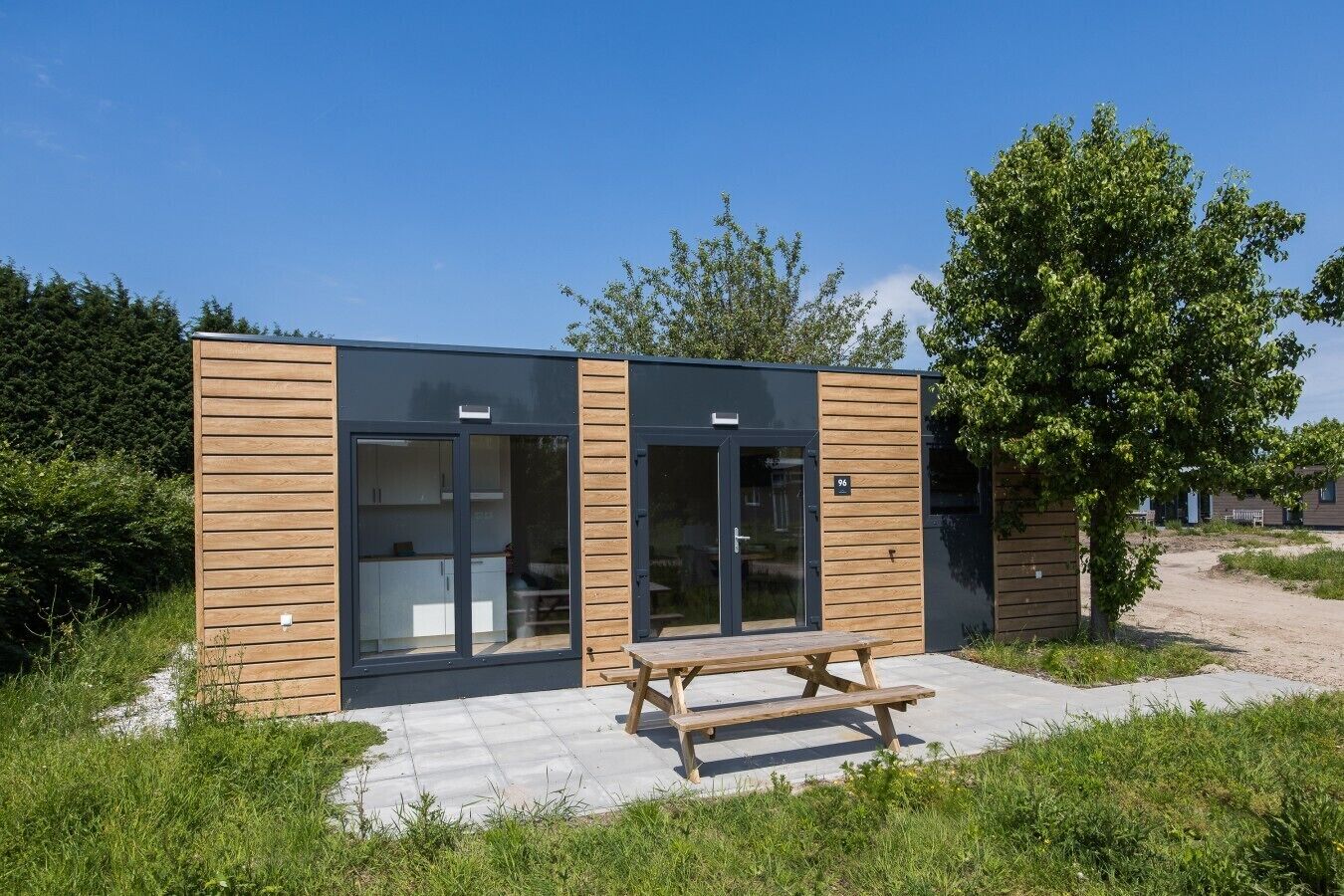 Un edificio moderno con fachada de madera, puertas de cristal amplias y una mesa de picnic al frente.