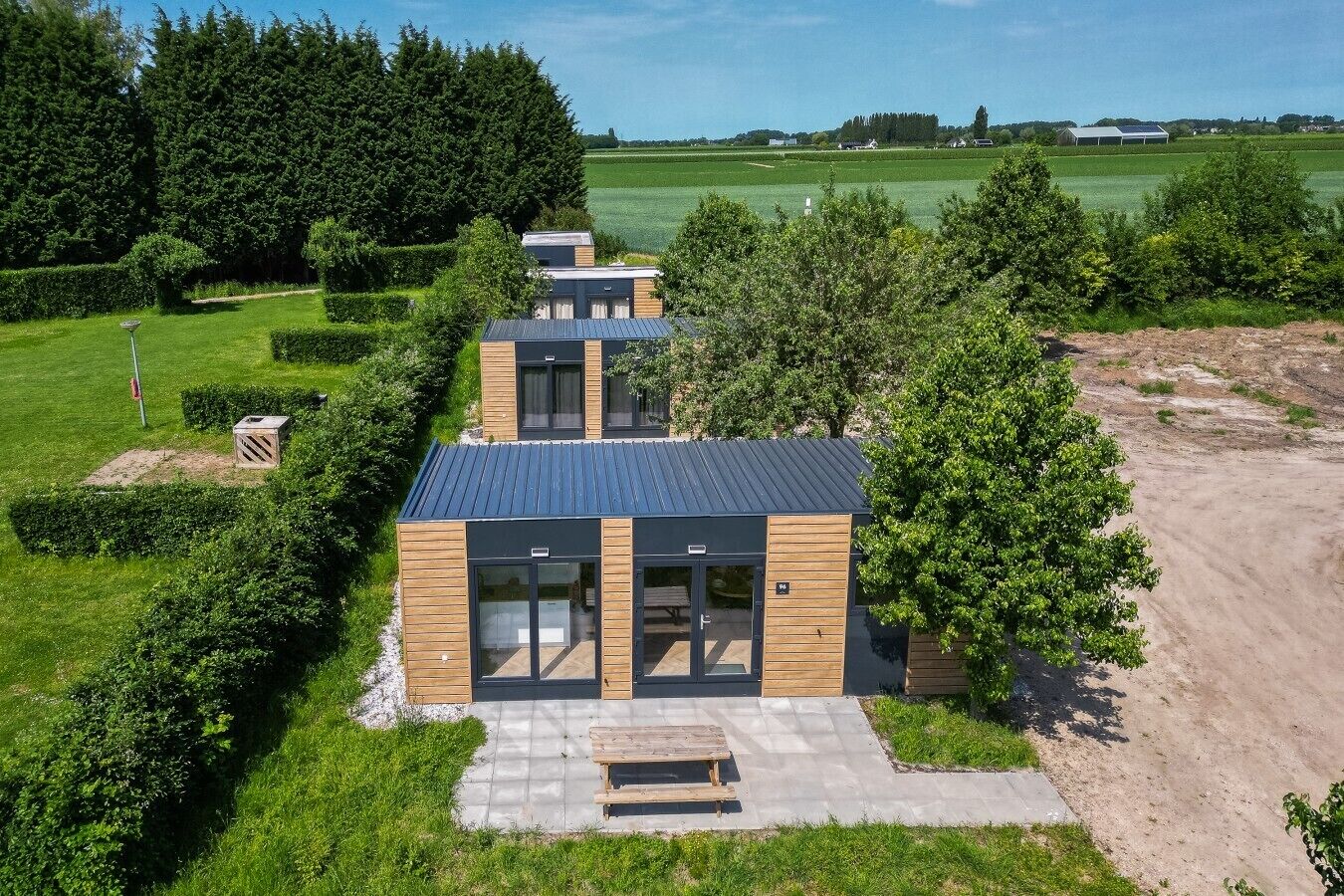 Een modern gebouw met een plat dak, grote ramen en een verhard entreegebied.