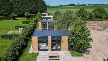 Een modern gebouw met een plat dak, grote ramen en een verhard entreegebied.