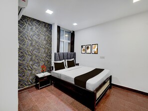 Ein Schlafzimmer mit Bett, Nachttisch, Fenster und Wand mit geometrischem Muster.