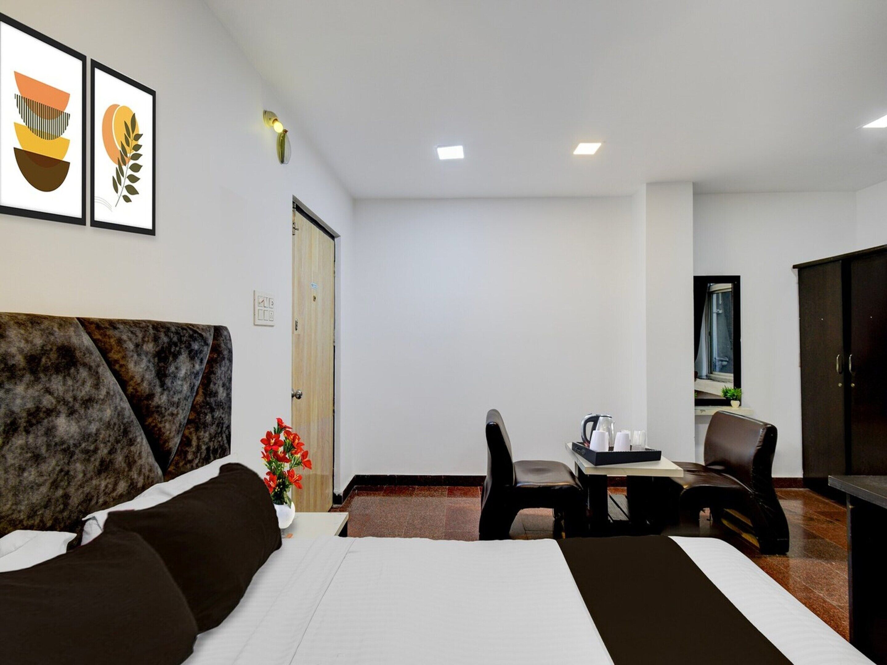 A hotel room with a bed, a desk, a chair, a television, and framed artwork on the wall.