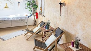 Une pièce comprenant un lit, une petite table avec des chaises, une lampe fixée au mur et une plante en pot.