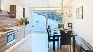 Une cuisine moderne avec un coin repas, un plancher en bois et une vue sur un paysage enneigé.