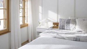 Une chambre à coucher avec un lit, une table de chevet, une lampe et une fenêtre avec des rideaux.