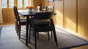 Un coin repas avec un mur lambrissé en bois, une table avec des chaises, un luminaire suspendu et des tableaux encadrés.
