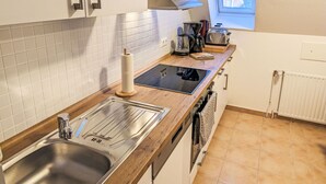 Una cocina moderna con un lavamanos de acero inoxidable, un horno empotrado, un tostador y una ventana con vista a una casa.