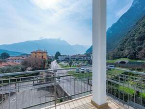 Ein Balkon mit Blick auf eine Straße, Gebäude und Berge.