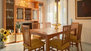 Un coin repas avec une table et des chaises en bois, un buffet avec des portes en verre et un vase rempli de tournesols.