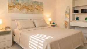 Une chambre à coucher avec un lit, des tables de chevet, un bureau, une chaise et un tableau au mur.