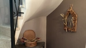 A staircase with a basket on a table, a wall-mounted mirror, and a textured wall. - Mas des Chênes.  Private spa. Nature and tranquility   (La Baume-de-Transit)