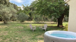 A backyard with a hot tub, two Adirondack chairs, and a small table with a bottle. - Mas des Chênes.  Private spa. Nature and tranquility   (La Baume-de-Transit)