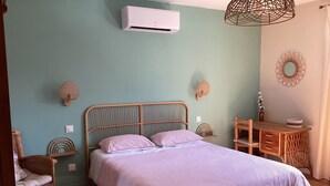 A bedroom with a bed, a desk, wicker furniture, and an air conditioning unit. - Mas des Chênes.  Private spa. Nature and tranquility   (La Baume-de-Transit)
