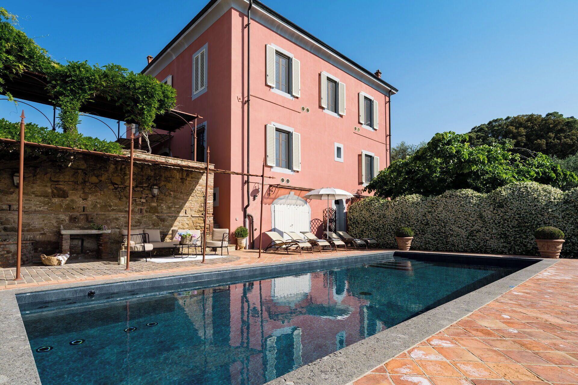 A poolside area with a stone wall, a lounge chair, and a table with a basket.
