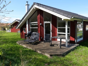 A red building with a covered deck, a grill, and outdoor seating. - 4 Star Holiday Home in Grossenbrode (Grossenbrode)
