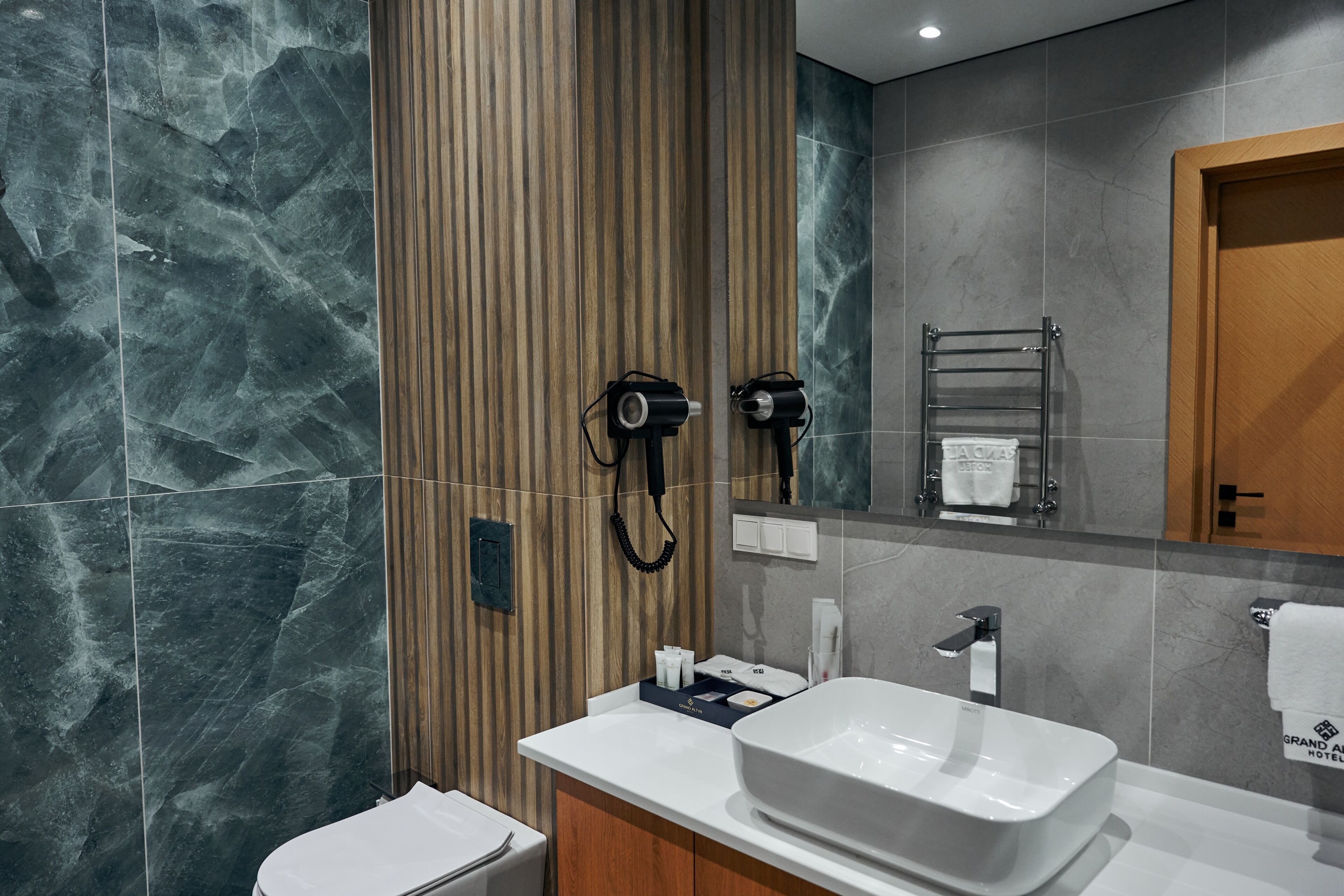 A modern bathroom with a large sink, towel rack, and a wooden panel wall.
