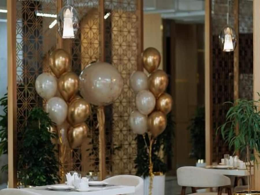 Un comedor con una mesa blanca, sillas de madera y una pared decorativa con un patrón geométrico.