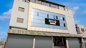 Un moderno edificio hotelero con una amplia fachada de vidrio, un llamativo letrero 'HOTEL' y un techo metálico.
