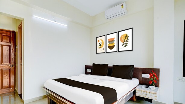 Habitación de hotel con cama, mesita de noche, aire acondicionado instalado en la pared y cuadros enmarcados.