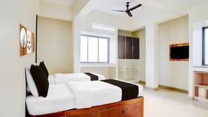 Un dormitorio con cama, ventilador de techo, televisión y ventana.
